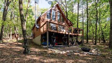 A cabin with a deck, surrounded by trees.