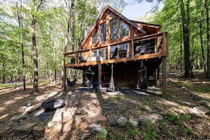 A wooden cabin with a balcony, surrounded by trees.