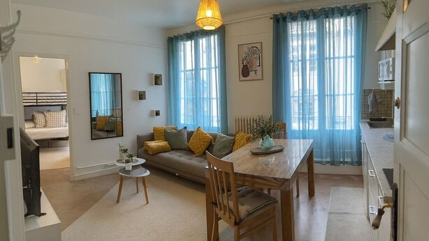 A modern living room with a sofa, a dining table, and a kitchen area visible through an open door. - Bright and renovated, City center (Vitry-le-François)