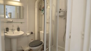A bathroom with a white sink, toilet, and glass shower enclosure. - Bright and renovated, City center (Vitry-le-François)