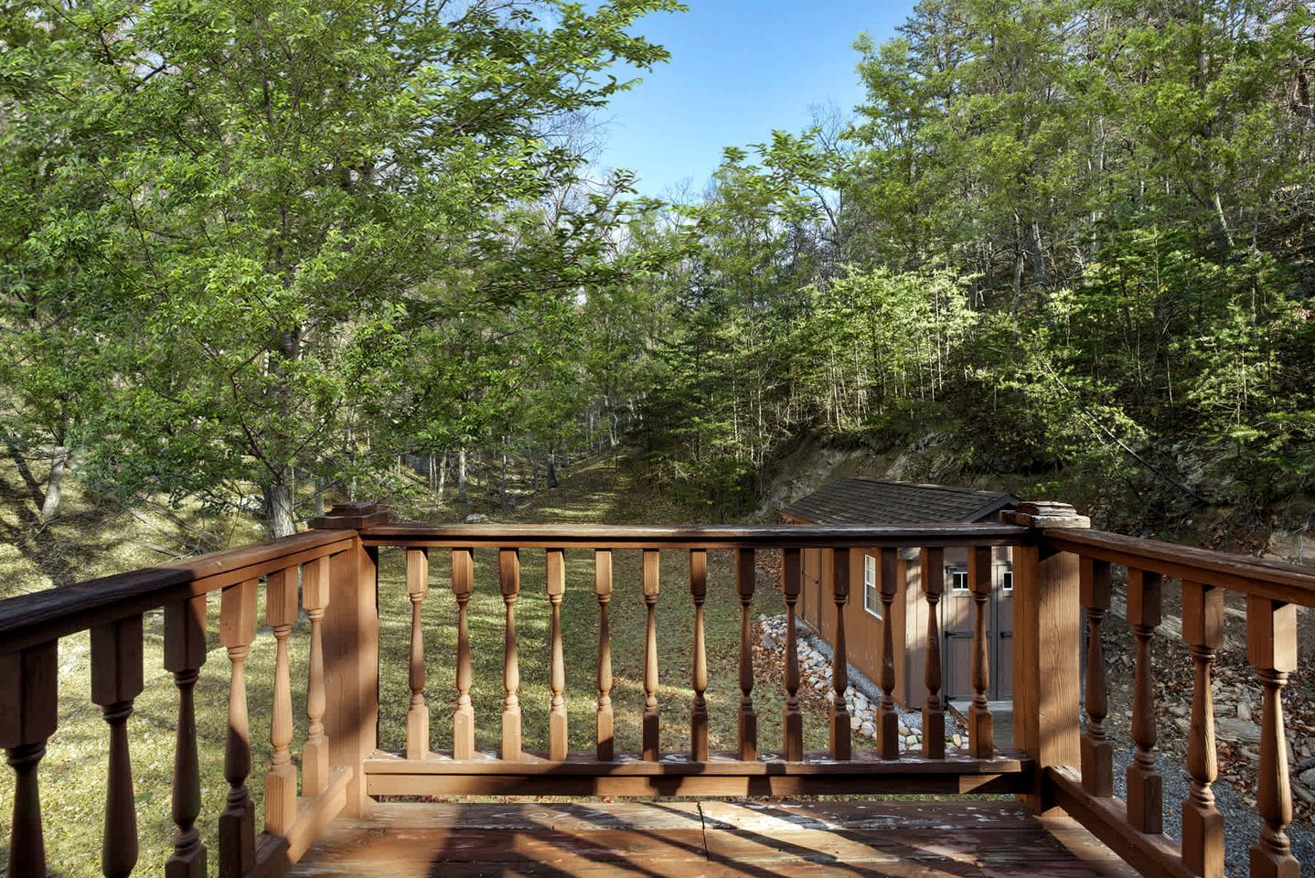 A wooden deck with a railing overlooking a forested area.
