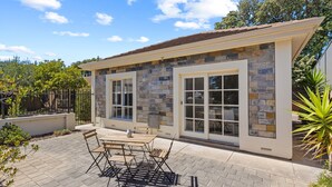 A modern house with a stone facade, large windows, and a patio with outdoor furniture.