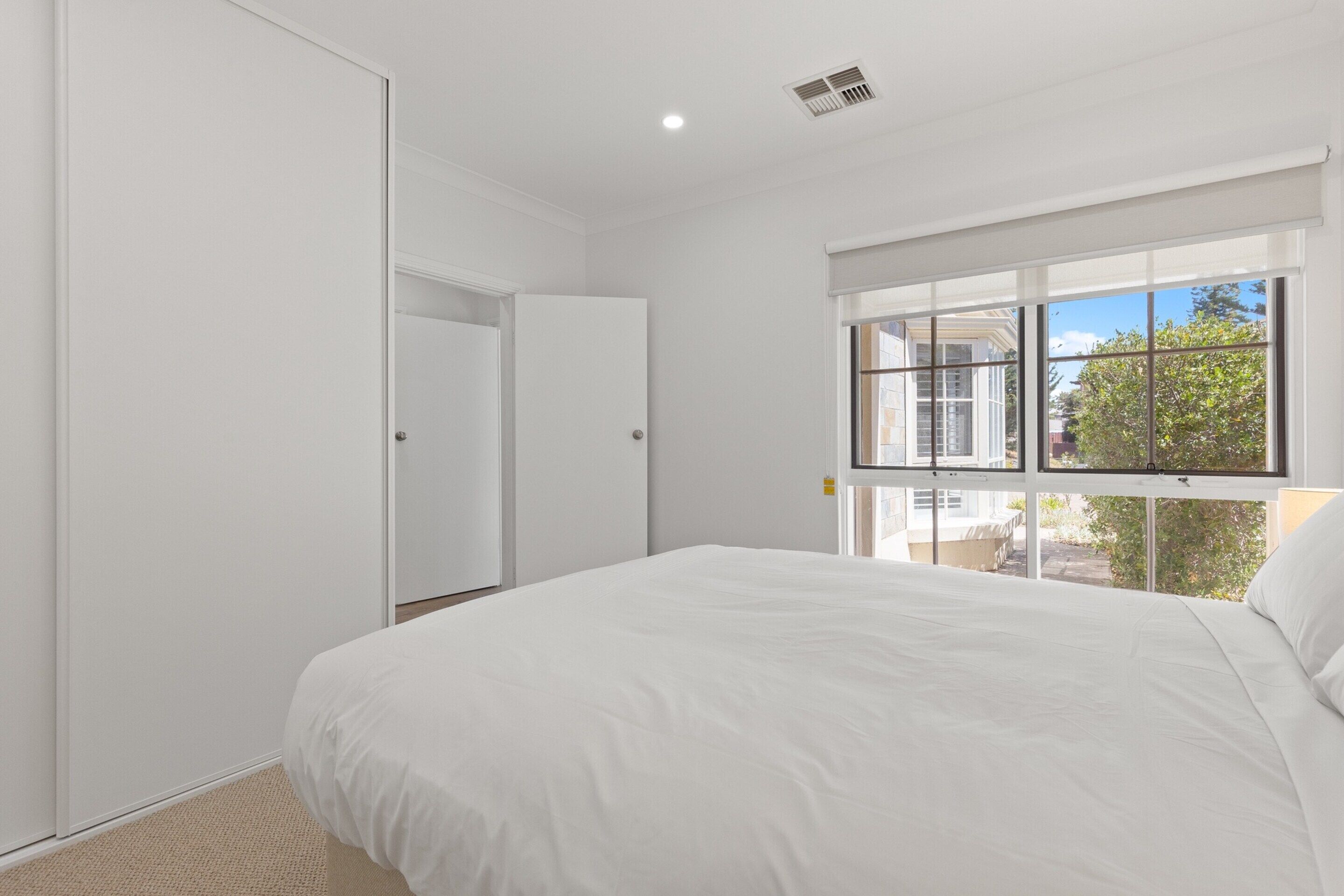 Un dormitorio con una cama grande, una ventana con vistas al exterior y una puerta cerrada.