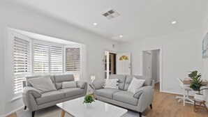A modern living room with two grey sofas, a white coffee table, and a small side table with a lamp.