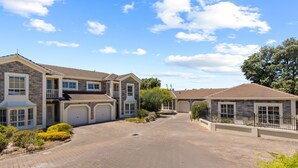 A residential street with houses featuring stone facades, multiple garage doors, and a paved driveway.