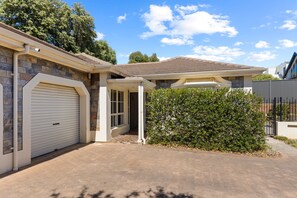 Uma casa residencial com garagem, fachada de pedra e um jardim da frente bem cuidado.