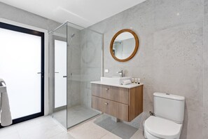 Ein modernes Badezimmer mit Duschkabine aus Glas, einem Holzbadezimmerhocker und einer Toilette.