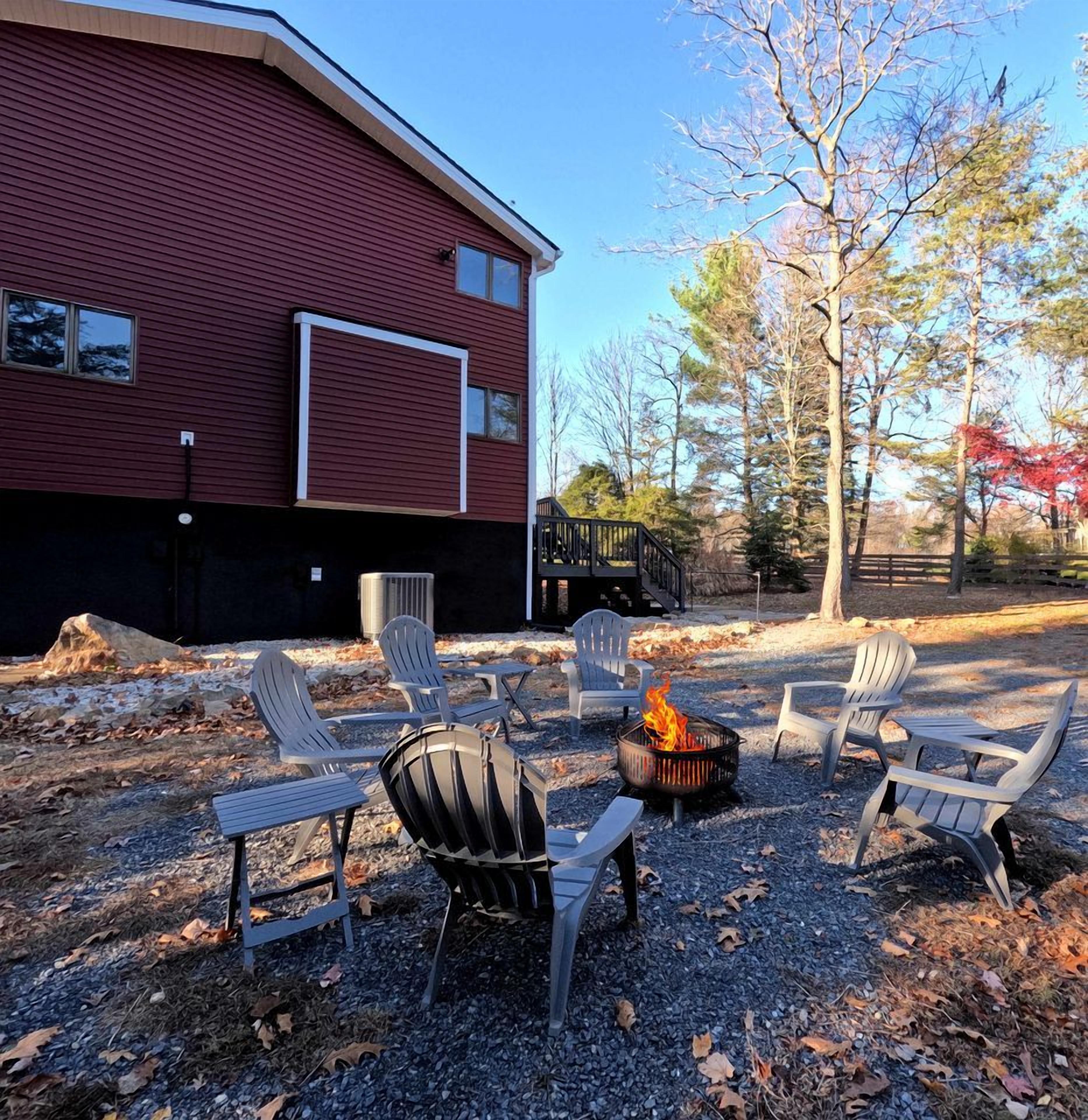 A building with a red exterior, a deck, and outdoor seating with chairs and a fire pit.