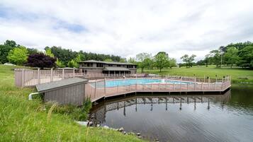 A swimming pool with a wooden deck and a building in the background.