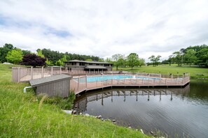 A swimming pool with a wooden deck and a building in the background.
