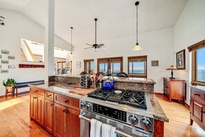 A spacious kitchen with granite countertops, a large stove, and a ceiling fan.