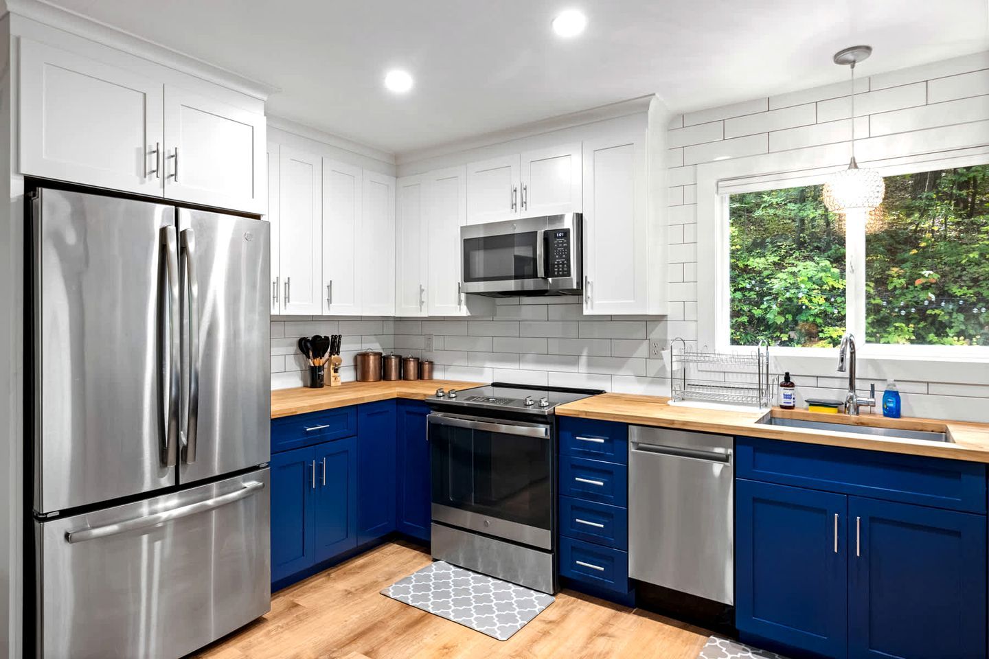 Una cocina moderna con electrodomésticos de acero inoxidable, armarios azules y una encimera de madera.