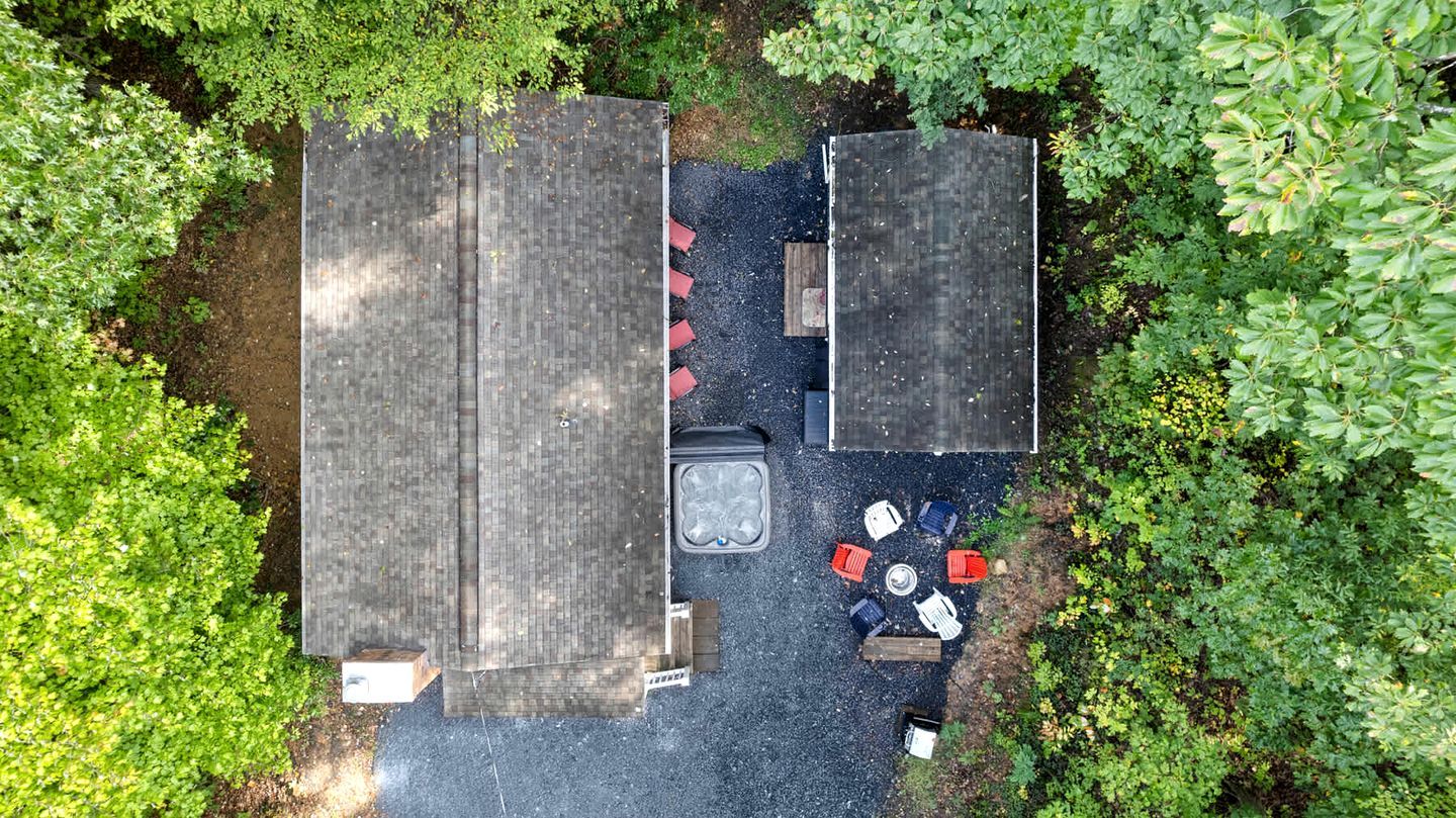 An aerial view of a patio area with two wooden tables and chairs, surrounded by greenery.