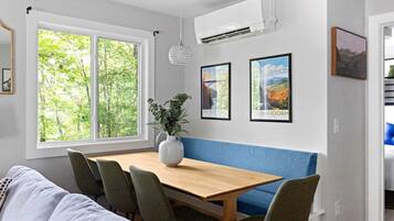 A dining area with a wooden table, chairs, a vase with plants, and framed pictures on the wall.
