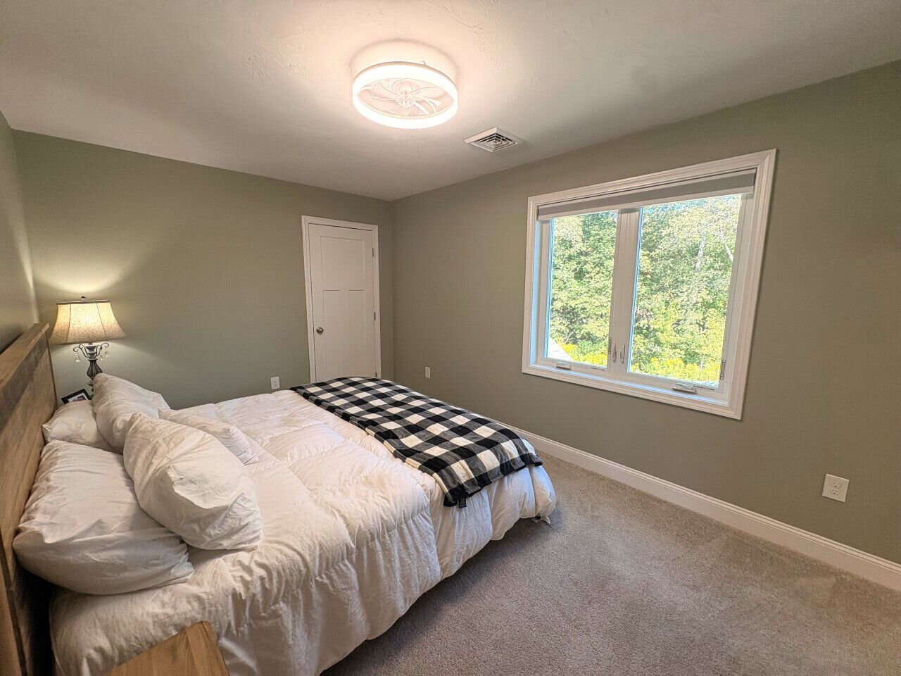 A bedroom with a bed, a window, and a door.