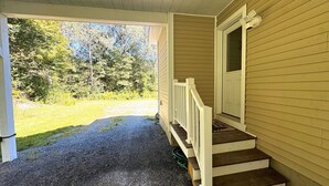 Un portico coperto con una scala in legno che conduce a una porta.