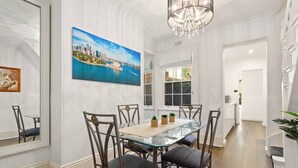 A dining area with a glass table, metal chairs, and a chandelier.