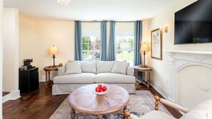 A living room with a sofa, a coffee table, a fireplace, and a television. - Romantic Mountain Vacation Rentals with Garden Views near Shenandoah National Park Virginia (Luray)