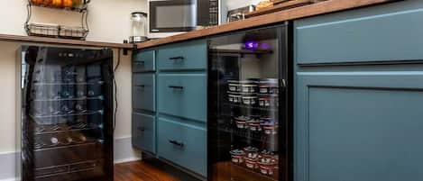 A kitchen with a built-in oven, a microwave, and a refrigerator with a wine rack.