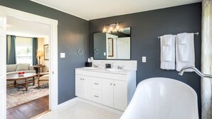 A modern bathroom with a white bathtub, a large mirror, and a vanity with a sink. - Romantic Mountain Vacation Rentals with Garden Views near Shenandoah National Park Virginia (Luray)