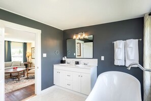 Une salle de bain moderne avec une baignoire blanche, un grand miroir et un meuble-lavabo.