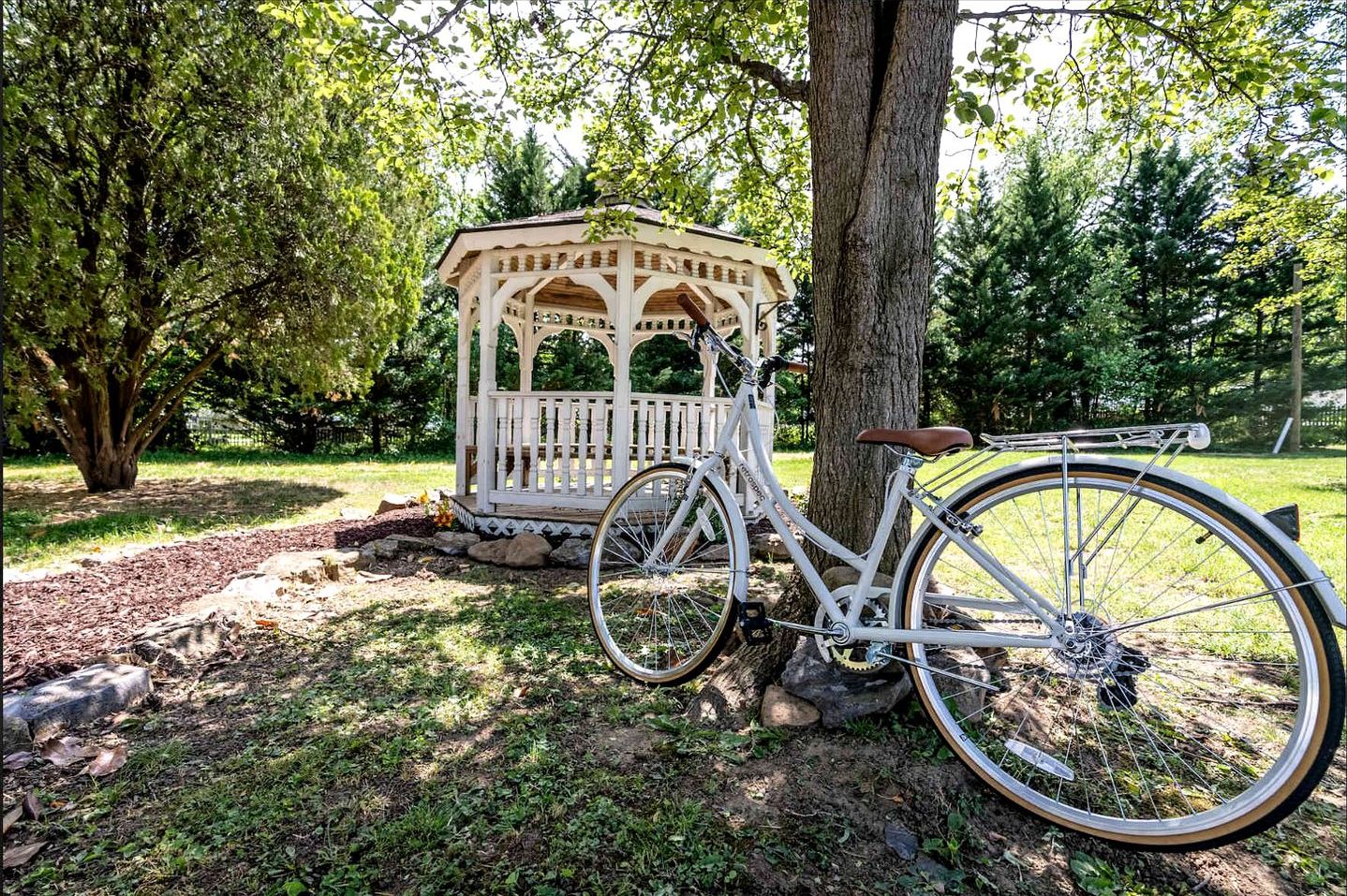 A gazebo, a bicycle, and a tree in a park setting.