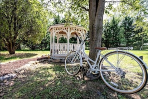 A gazebo, a bicycle, and a tree in a park setting.