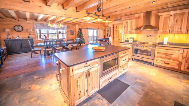 Cucina spaziosa con mobili in legno, un'isola grande e pavimento in pietra.