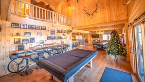 Interno di una baita in legno con angolo bar, tavolo da pranzo e albero di Natale.