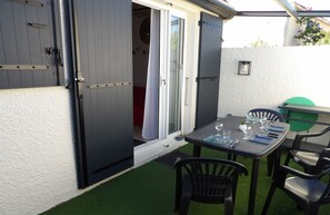 Eine offene Terrasse mit Esstisch, Stühlen und einer Schiebetür zu einem Raum.