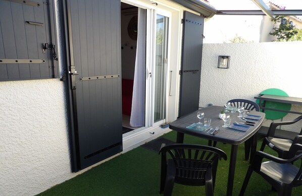 An open patio with a table set for dining, chairs, and a sliding door leading to a room. - St Cyprien charming haven near the beach (Saint-Cyprien)