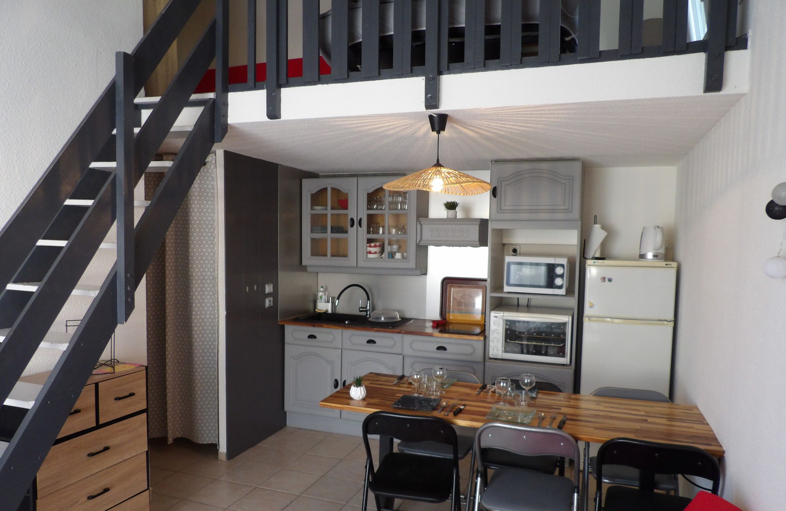 Une cuisine de taille réduite comprenant un coin repas, un escalier et un four à micro-ondes.