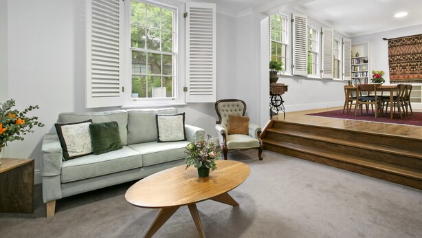 Un salón espacioso con un sofá verde claro, una mesa de centro de madera y un comedor con mesa y sillas de madera.