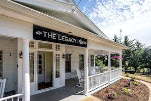 A white building with a porch, a sign reading 'The Legacy Inn,' and a number '120' on the wall. - Lavish Mountain Vacation Retreat with Blue Ridge Views near Shenandoah National Park Virginia (Luray)