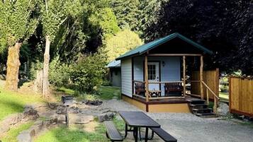 En liten stuga med en veranda, ett picknickbord och trappsteg som leder upp till ingången.