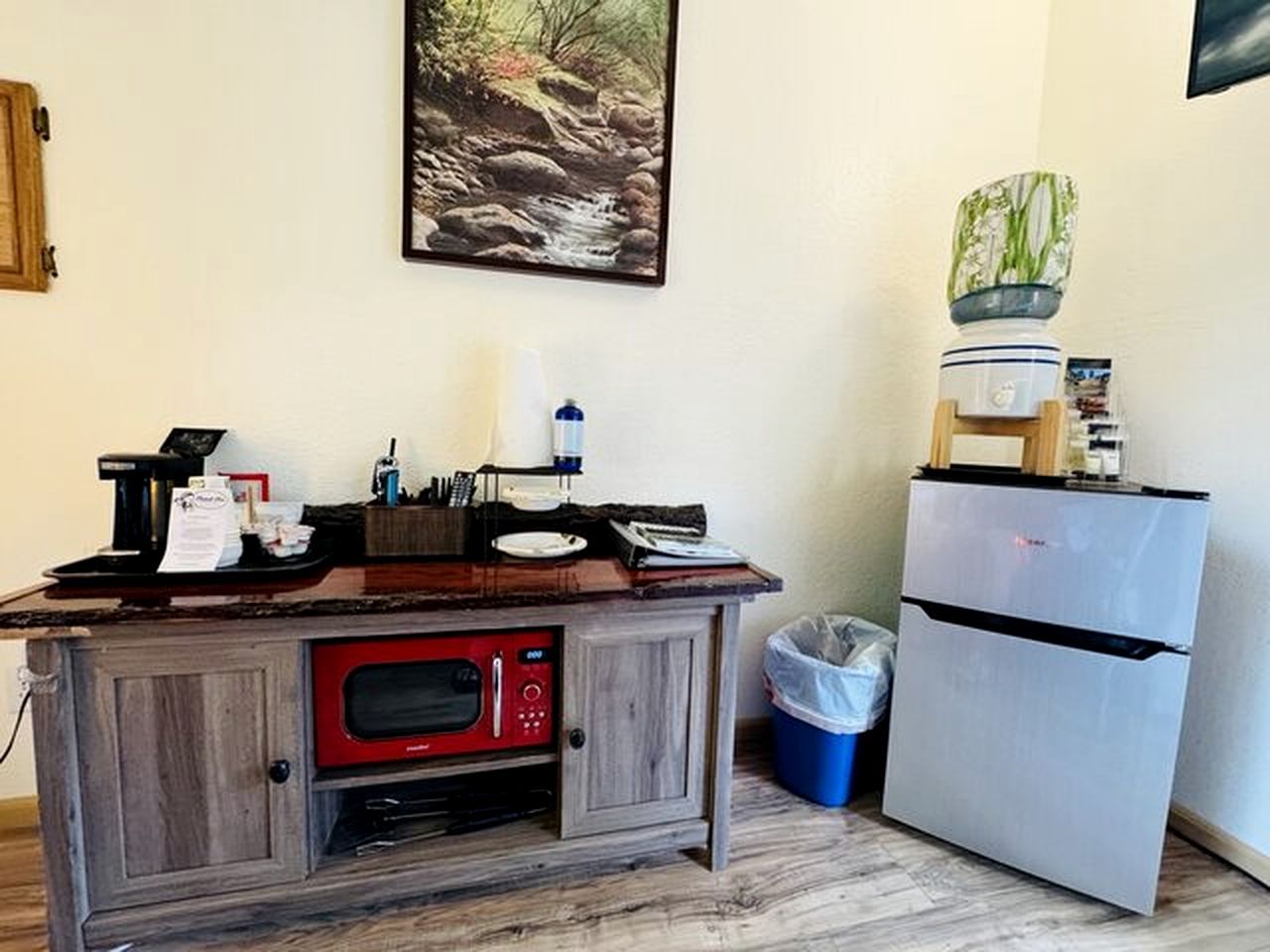 A kitchenette with a microwave, a small refrigerator, a sink, and a trash bin.
