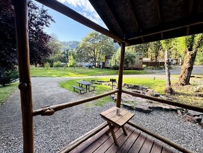 A wooden deck with picnic tables and a view of a park and mountains.
