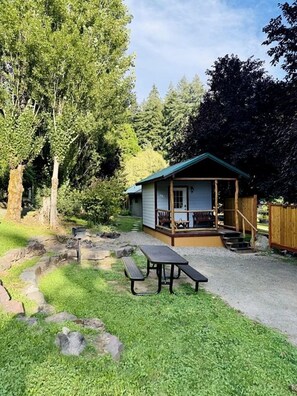 Eine kleine Holzhütte mit Veranda, Picknicktisch und Treppe zum Eingang.