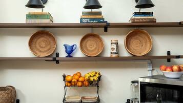 A kitchen with shelves holding books, woven baskets, and a fruit basket.