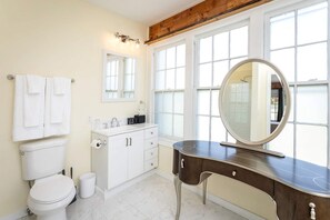 Ein Badezimmer mit Toilette, Waschbecken, Waschtisch und großen Fenstern.