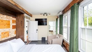 Een hotelkamer met een bed, een stoel, een televisie en een raam met gordijnen.