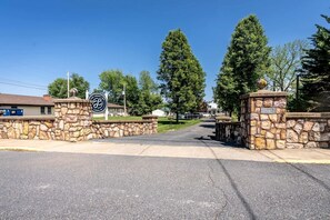 A stone gate with a sign for The Legacy Inn, a paved driveway, and surrounding trees.