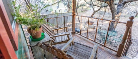 A wooden deck with a railing, a potted plant, and a bench.