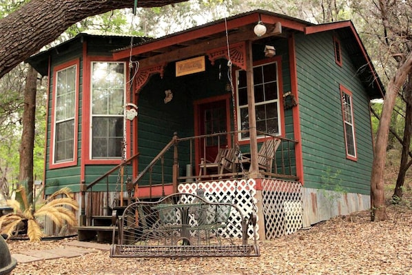 A rustic cabin with a porch, large windows, and a small porch swing.