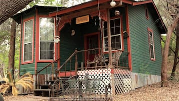 A rustic cabin with a porch, large windows, and a small porch swing.