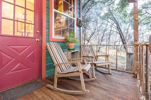 Une terrasse en bois avec des fauteuils à bascule et une plante en pot.