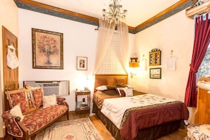 Une chambre à coucher comprenant un lit, un canapé, une table de chevet, un lustre et une fenêtre avec des rideaux.