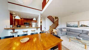 Ein modernes Interieur mit Essbereich, Küche, Treppe und Wohnzimmer.