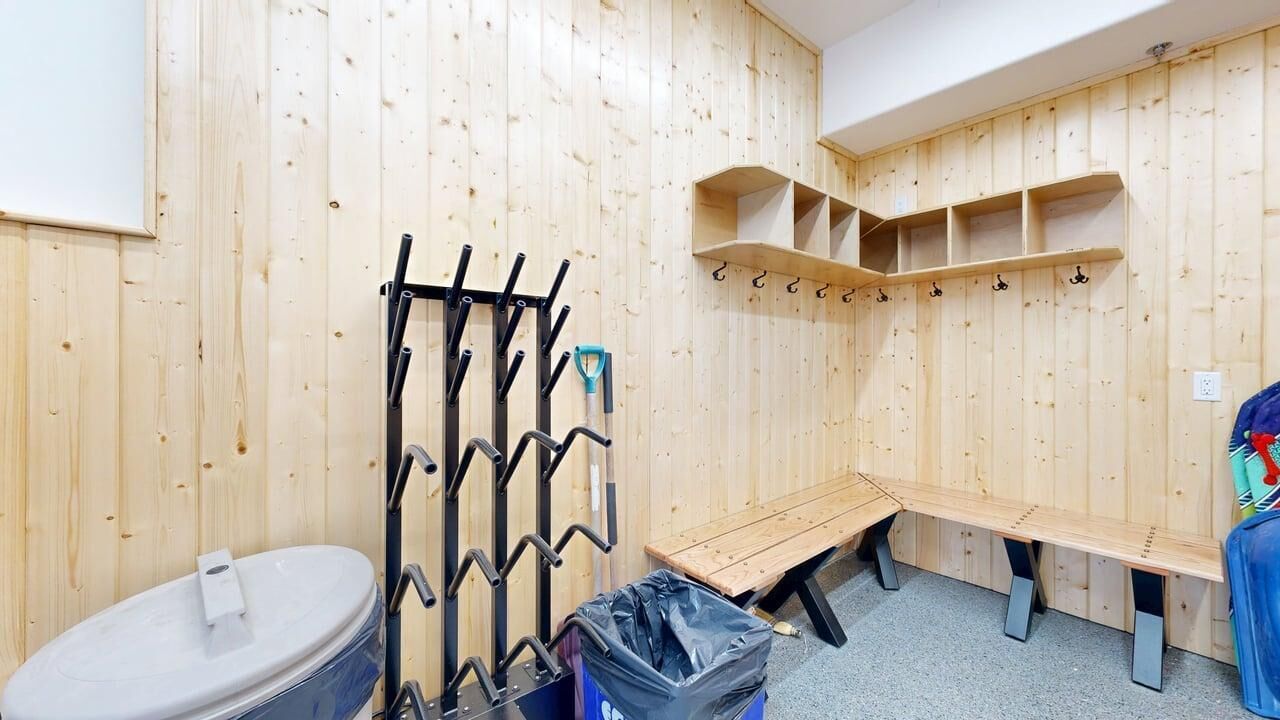 Ein Zimmer mit Holzwänden, einer Sitzbank, einem Waschbecken und einem Hakenständer.