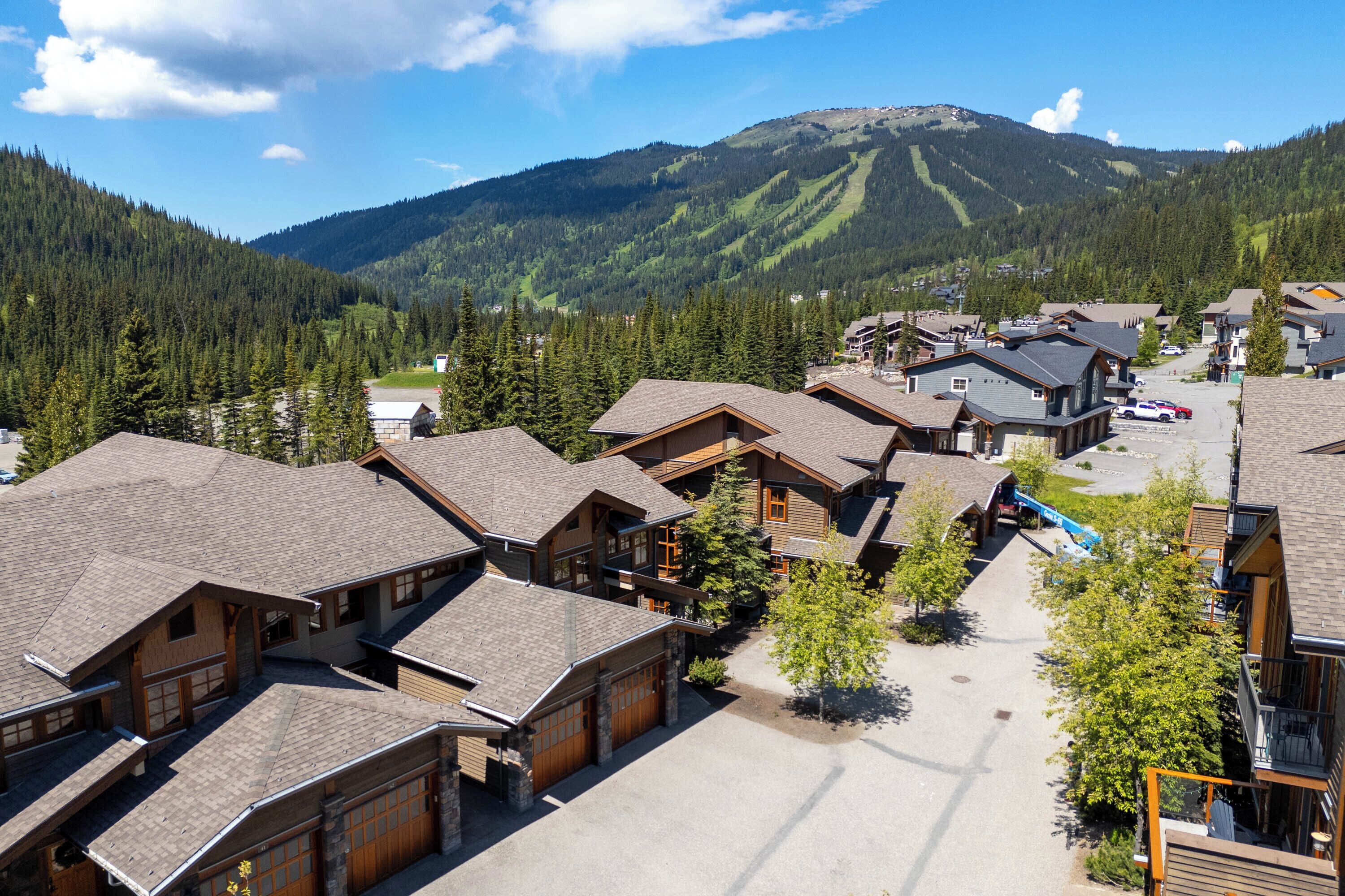 Et fjeldhotel med flere bygninger, stolelift og skov i baggrunden.